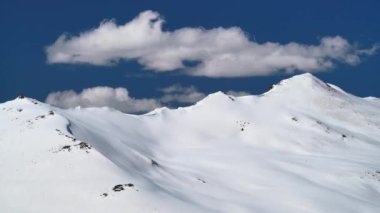 8K 7680X4320 4320p.White cumulus cloud in the blue sky on the treeless snowy hill.Mountains on a sunny winter day.Mount partly cloudy fluffy background landscape view nature snow snows mountainous higher terrain geography topography slope ridge