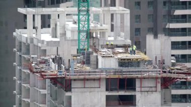 Cinematic 8K 7680x4320.Cranes and construction workers working at a major.Builders on building site.Transporting wall molds at skyscraper.Concrete and iron combination.Yellow crane mixed compex crowd.business, urban, city, complex, industrial,