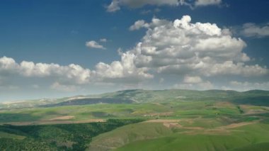 8K 7680X4320 4320p.Cumulus bulutları ağaçsız, seyrek fırçalanmış tepeler üzerinde. Kırsal bölgeler kırsal iklimde parçalı bulutlu hava. Zaman aralığı. Panoramik pan manzarası. 8K