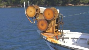 Küçük balıkçı teknesinde ağ çekme ağı. Küçük plastik şamandıralara bağlı naylon balıkçı ağı. Eski teknede balık ağı makarası. Arka planda mavi okyanuslu küçük balıkçı teknesinde ağ ağ mekanizmasına yakın çekim. 
