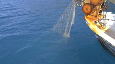 Küçük balıkçı teknesinde ağ çekme ağı. Küçük plastik şamandıralara bağlı naylon balıkçı ağı. Eski teknede balık ağı makarası. Arka planda mavi okyanuslu küçük balıkçı teknesinde ağ ağ mekanizmasına yakın çekim. 