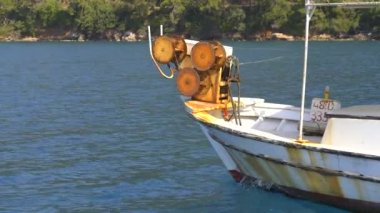 Küçük balıkçı teknesinde ağ çekme ağı. Küçük plastik şamandıralara bağlı naylon balıkçı ağı. Eski teknede balık ağı makarası. Arka planda mavi okyanuslu küçük balıkçı teknesinde ağ ağ mekanizmasına yakın çekim. 