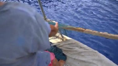 4K. Balıkçı, geleneksel yöntemle denizdeki balıkçı ağını çekiyor. Balıkçı ağı, insan gücüyle balıkçı teknesine çekiliyor. Ağır iş.