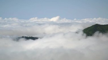 8K 7680x4320. Bulutlar denizi bulutların tepesindeki dağlardan yükseliyor. Yağmur ormanları üzerindeki sislerin üzerinde.Nemli ve nemli hava akımı. Bulutlu pamuk bulutu bulutu bulutu. Zaman akışı .8K