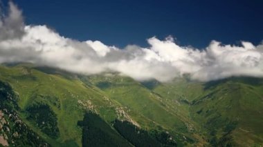 8K 7680x4320. Alp dağlarındaki alçak tepeler. Ormanda açık alan. Güneşli ve bulutlu bir gökyüzü. Alpler en yüksek sıradağlardır..