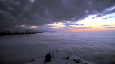 8K 7680x4320. Gün batımından sonra dağlardaki bulutlar üzerinde. Renkli günbatımı gökyüzü. Doğada zaman kaybı..
