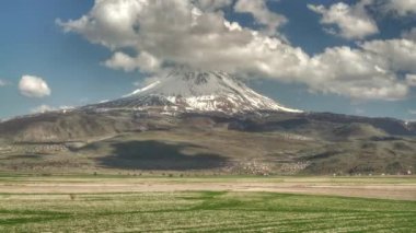 8K 7680X4320.Volkanik dağ düzlüklerde yükseliyor. nowy koni tepesi. Zaman bulutlu güneşli bir günde doğayı hızlandırıyor. Dağlık yüksek arazi coğrafyası topoğrafyası bayır tepe tepe tepeleri zirvesi tepeleri