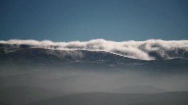 8K 4320p 7680x4320.Bulut dağ sıralarından aşağı akıyor. Tepelerin kıvrımlarında yatan sis. Ağaçsız karasal alanlar. Baharda tepeler. Doğada güneşli standart bir gün. Sis kayboluyor..