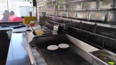 8K 7680x4320.Burgerciler hamburgercide pişiyor. Şef, şişko köftelerde çalışıyor. Caddelerin kenarındaki hamburgercide. Fast food restoranının tezgahı atölye eti, kızarmış patates yapıyor.