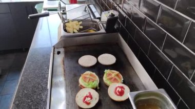 8K 7680x4320.Burgerciler hamburgercide pişiyor. Şef, şişko köftelerde çalışıyor. Caddelerin kenarındaki hamburgercide. Fast food restoranının tezgahı atölye eti, kızarmış patates yapıyor.