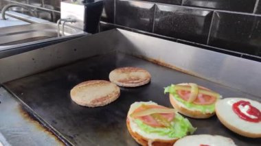 8K 7680x4320.Burgerciler hamburgercide pişiyor. Şef, şişko köftelerde çalışıyor. Caddelerin kenarındaki hamburgercide. Fast food restoranının tezgahı atölye eti, kızarmış patates yapıyor.
