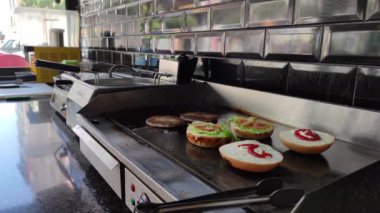 8K 7680x4320.Burgerciler hamburgercide pişiyor. Şef, şişko köftelerde çalışıyor. Caddelerin kenarındaki hamburgercide. Fast food restoranının tezgahı atölye eti, kızarmış patates yapıyor.