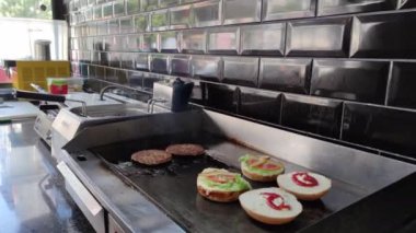 8K 7680x4320.Burgerciler hamburgercide pişiyor. Şef, şişko köftelerde çalışıyor. Caddelerin kenarındaki hamburgercide. Fast food restoranının tezgahı atölye eti, kızarmış patates yapıyor.