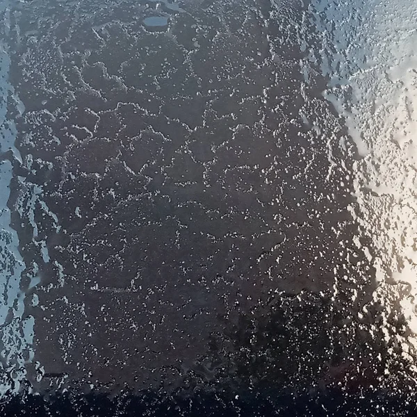 Las heladas en el parabrisas, los rayos del sol de la mañana derriten las heladas formadas durante la noche. Fondo, textura. — Foto de Stock
