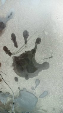 Donmuş bardakta avuç içi izi var. Ellerini ve parmaklarını kar ile kaplı pencereye koy..