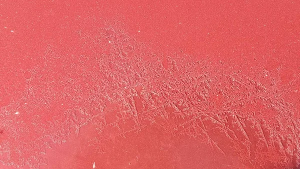 Frost på metallytan av bilen med en röd oskärpa effekt. Abstrakt bakgrund och struktur för design. — Stockfoto