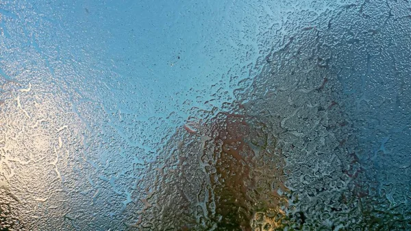 Замерзшее лобовое стекло. Гранулярная структура прозрачного льда. Небо светит сквозь него. Абстрактный фон льда. — стоковое фото