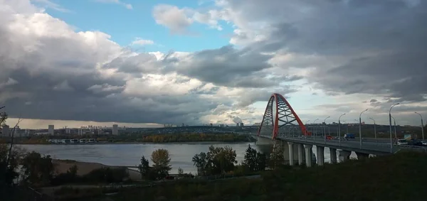 Červený oblouk visutého visutého mostu přes širokou řeku Ob. Novosibirsk, Rusko. — Stock fotografie