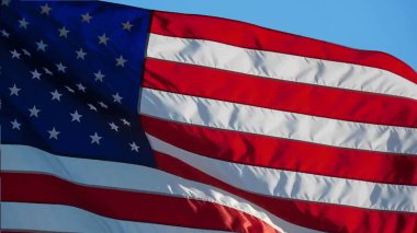 Mavi arka planda esintide dalgalanan Amerikan bayrağı. Beyaz arka planda ABD bayrağı. Kapat.