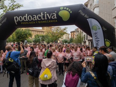 22 Ekim 2022 'de Huesca şehrinde göğüs kanserine karşı yarışan koşucular göğüs kanserine katılan mutlu kadınların park portresinde finiş çizgisini geçerek tezahürat yaptılar.