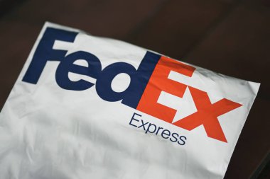 FedEx Express paketi. Karanlık masa arkaplanındaki FedEx nakliye çantasının yaşam tarzı resmi