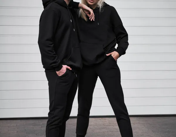 女性と男性はロゴなしで黒いパーカーを着用します ロゴは基本的なスポーツウェアではない 長袖のトレーナーのモックアップ — ストック写真