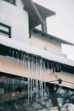 Eriyen buz saçakları çatıdan sarkıyor. Dışarıda eriyen kar ve buz yüzünden risk ve hasar kavramı
