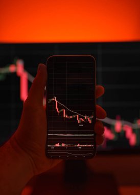 Cep telefonu ve bilgisayar ekranı şifreli para birimi grafiği gösteriyor. Çevrimiçi ticaret. Kırmızı arkaplanlı bitcoin döviz kuru kavramı