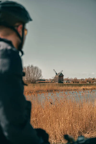 Kasklı bir bisiklet silueti ve mirastır ahşap bir yel değirmeni. Açık havada aktif yaşam kavramı. Kırsal ve kırsal alan maceraları.