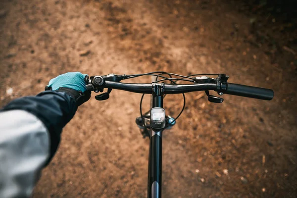 First-person view bicycle riding. Man riding a bike. holding bike handlebar with one hand in sport glove. Summertime outdoor leisure sport activity. Close up of bicycle handle bar