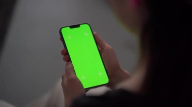 Akıllı telefonunu kapalı mekanda kullanan bir kadına yaklaş. Oturma odasında ekranda ekranı görünen bir kızın yeşil ekran modeli..