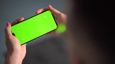 Bir adam akıllı telefonu yatay olarak iki eliyle tutar. Anahtar modeli için yeşil ekran. Yavaş çekim videosu izleniyor