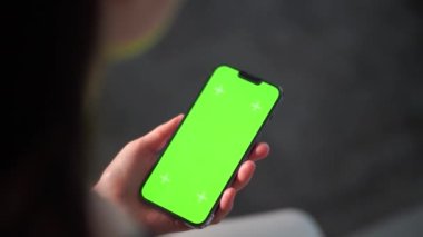 Oturma odasındayken bir kız telefonunu tutuyor. Tek eliyle akıllı telefon kullanan bir kadına yaklaş. Anahtar için yeşil ekran modellemesi