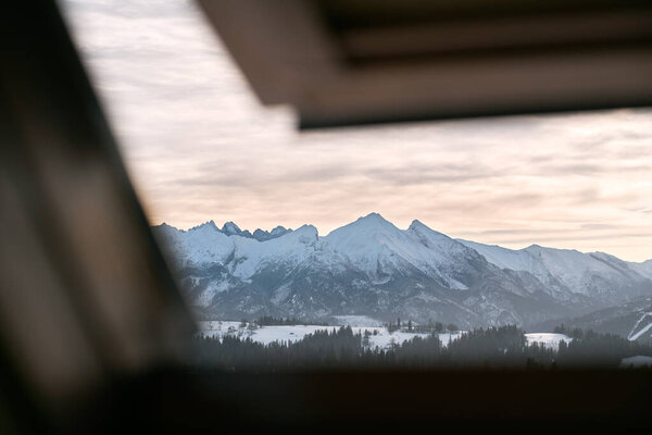 Roof window view of a severe winter weather view in the mountains. Concept of winter vacation during winter holidays in cozy cottage