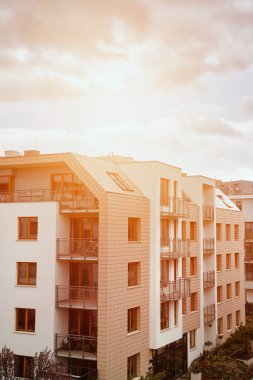 Gün batımında apartmanda. Akşamları apartman inşaatı var. Düşük seviyeli modern konut binasına güçlü güneş ışığı düşüyor.