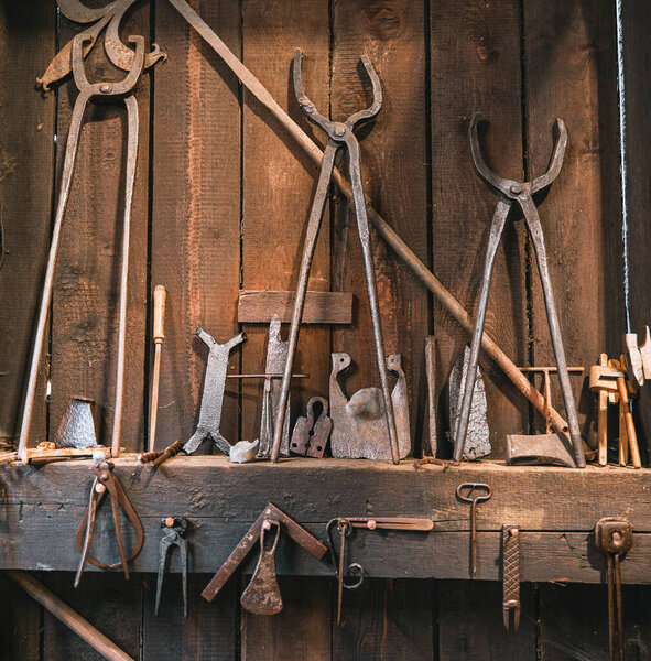 Traditional blacksmiths hardware and instruments. Concept of working in the workshop. Close up details of tools that were used to work with iron, weapons, and armor.