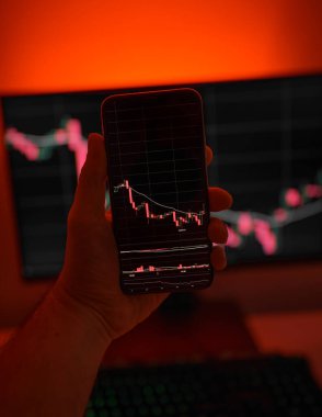 Cep telefonu ve bilgisayar ekranı şifreli para birimi grafiği gösteriyor. Çevrimiçi ticaret. Kırmızı arkaplanlı bitcoin döviz kuru kavramı