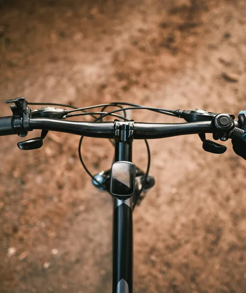 Top view of mountain bike handlebar and blurred cross country forest road. Concept of extreme activity on the woods trails.