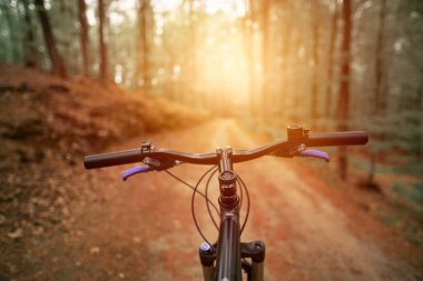 Güçlü güneş ışığıyla bisiklet gidonuna bakan ilk kişi.