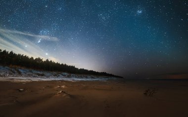 Kumlu bir sahilde Samanyolu Galaksisi. Yaz tatilinde deniz kenarında yıldızları izliyoruz..