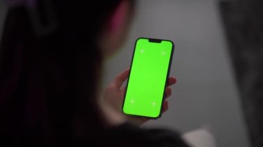Akıllı telefonunu kapalı mekanda kullanan bir kadına yaklaş. Oturma odasında ekranı görünen bir kızın yeşil ekran modeli..