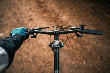 First-person view of handling the bicycle on the forest road in the city towards sunlight. Concept of using a bicycle for sports and recreation out of a town.
