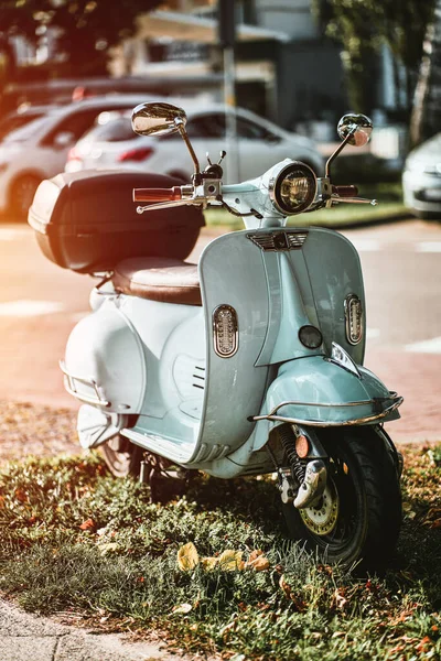 Antika, açık mavi bir scooter. Arka sokağın yanında duruyor. Avrupa sokaklarında elektrikli motosiklet paylaşımı
