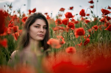 Kırmızı haşhaş tarlasında güzel bir genç kız. Çıplak omuzlu esmer kadın. Kırsal kesimde kadınların rahatlama ve mutluluk kavramı