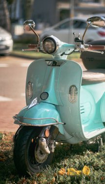 Antika, açık mavi bir scooter. Arka sokağın yanında duruyor. Avrupa sokaklarında elektrikli motosiklet paylaşımı