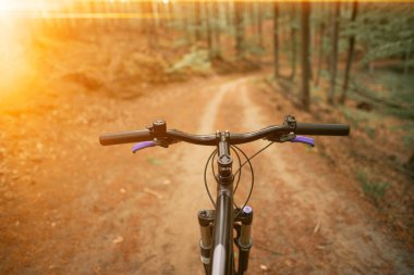 Güçlü güneş ışığıyla bisiklet gidonuna bakan ilk kişi.