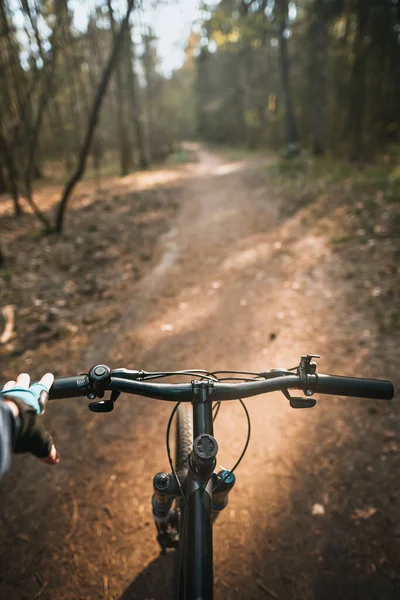 First-person view bicycle riding. Man riding a bike. holding bike handlebar with one hand in sport glove. Summertime outdoor leisure sport activity. Close up of bicycle handle bar