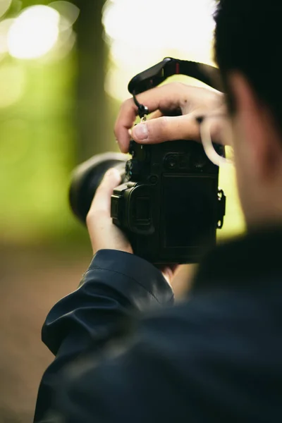 靠近一个拿着现代摄影相机的男人 一边看着屏幕 在屏幕可见的情况下关闭相机 业余爱好者在森林里拍照的概念 — 图库照片