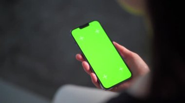 Akıllı telefonunu kapalı mekanda kullanan bir kadına yaklaş. Oturma odasında ekranı görünen bir kızın yeşil ekran modeli..