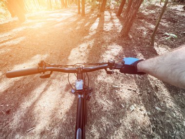 Ormanda çamurlu yolda bisiklet sürerken pov fotoğrafı. Orman geçmişi olan bir bisiklet gidonunun yakınında. Son derece kırsal ve açık havada bisiklet sürme kavramı.